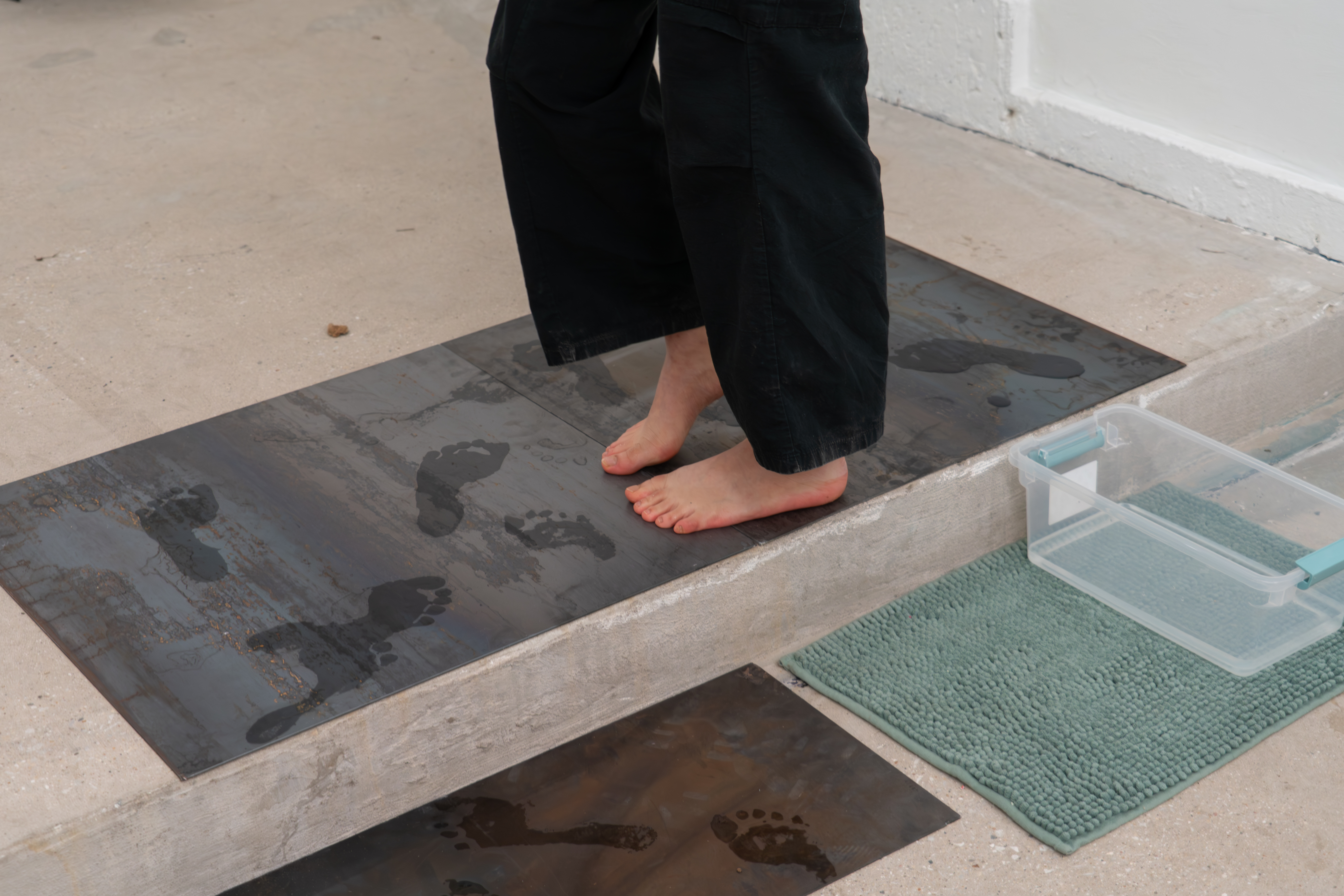 The Wake of the Body by oneg - ephemeral wet footprint traces on steel surface exploring presence and absence